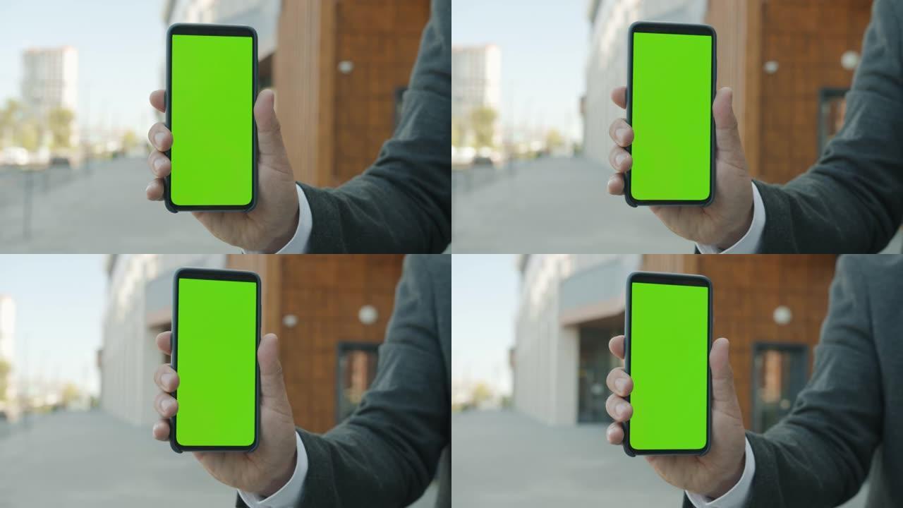 城市户外商人手持色键绿色智能手机屏幕的特写