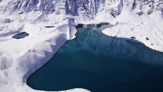 在明亮的阳光下，雪山中的高山湖泊的无人机镜头。雪山。蒂利乔湖