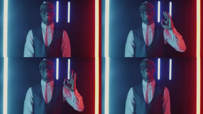 乐观的非洲裔美国商人的慢动作肖像在多色霓虹灯背景上显示OK手势