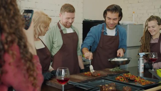 烹饪班学生用智能手机拍照时用火做饭的一组厨师