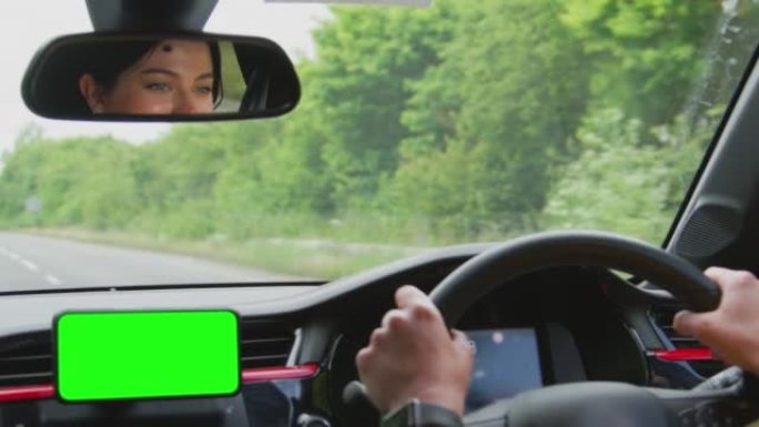 女人驾驶汽车的特写镜头，带免提装置，用于安装在仪表板上的绿屏手机-慢动作拍摄