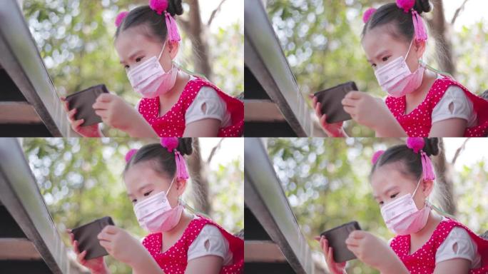 带防护口罩的亚洲小女孩打算看手机