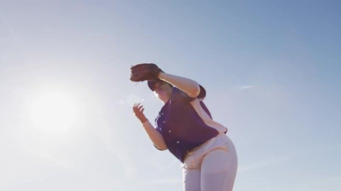 混血女棒球野手在阳光充足的棒球场接球投球