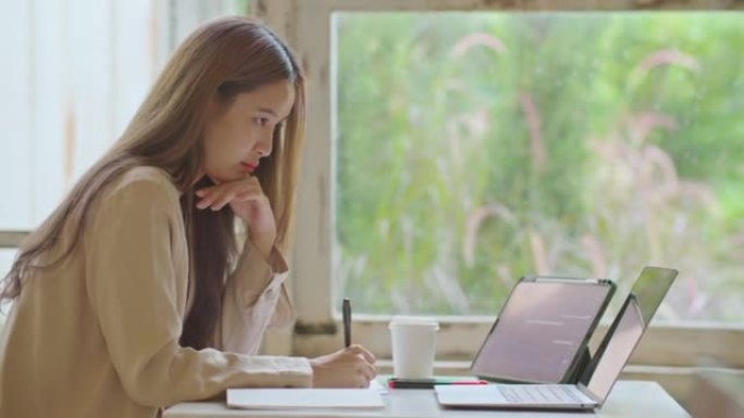 亚洲女性自由职业者在办公空间咖啡馆使用笔记本电脑远程工作。