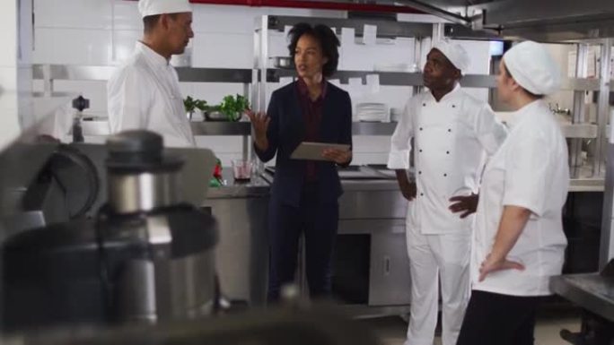 非裔美国女经理使用平板电脑并与厨师交谈