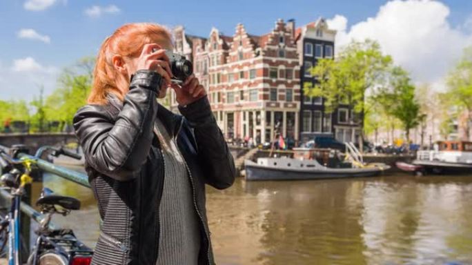 女人享受阳光明媚的日子，欣赏阿姆斯特丹的运河，用老式复古模拟相机拍照