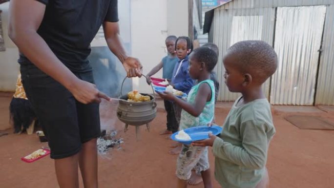 非洲的贫困。饥饿的非洲黑人儿童在慈善组织分发食物时伸出盘子