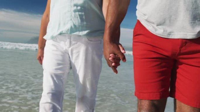 老年非洲裔美国夫妇的中段在海滩上散步和牵手