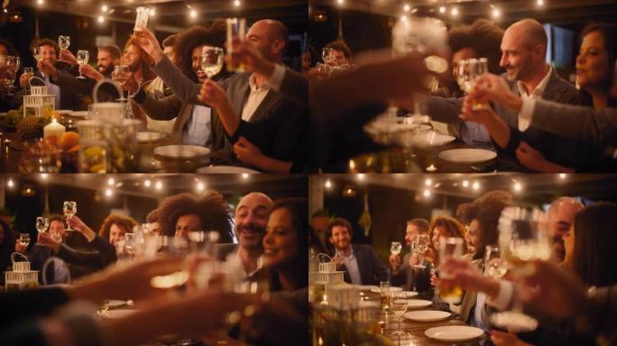 大型晚宴，一小群多种族的不同朋友在餐厅庆祝。美丽快乐的主人在晚上坐在桌子旁敬酒并举起酒杯。
