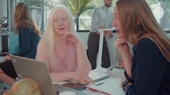快乐的年轻高加索白化女人在现代灯光办公室慢动作中用笔记本电脑与客户服务经理交谈。