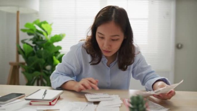 年轻女子检查账单并使用计算器进行家庭财务