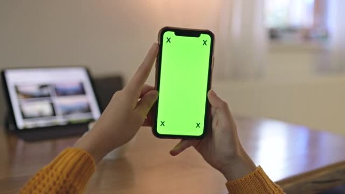 女士女士的手在家中使用带有色度键绿屏的智能手机