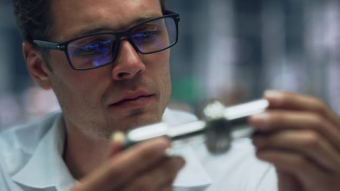 在汽车装配厂的办公室里，年轻英俊的工程师戴着眼镜在制造金属零件的特写肖像。工业产品设计师在生产前检查