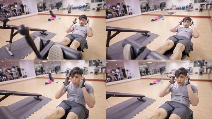 年轻人在健身中心的仰卧起坐长凳上进行腹肌锻炼。