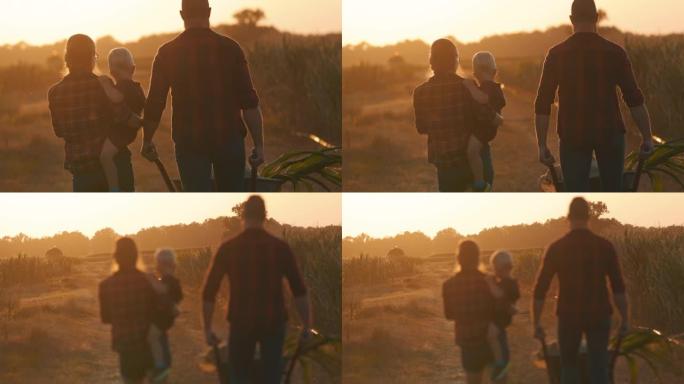 SLO MO的母亲背着孩子，而父亲在日落时推着装满农作物的独轮车