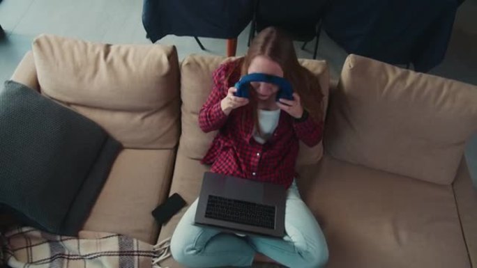 顶视图年轻迷人的千禧一代白人女商人使用笔记本电脑，戴上耳机在家在线工作。