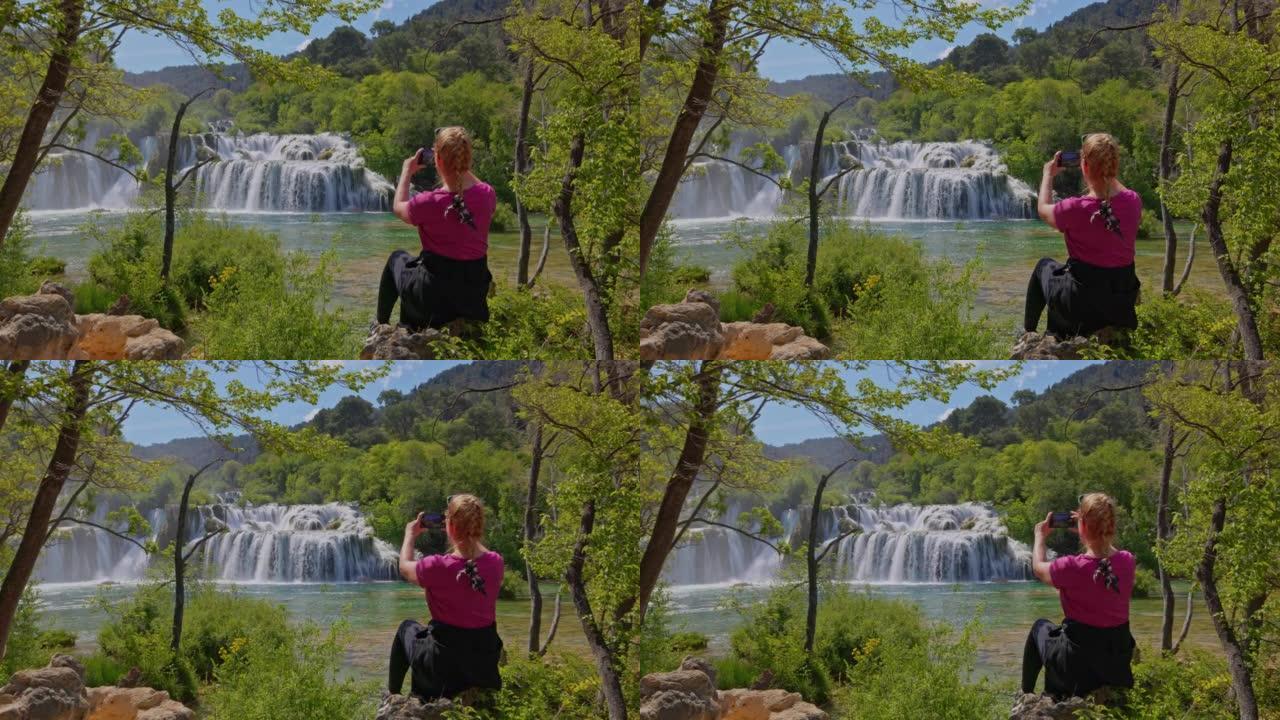 金发女人坐在岩石上在Krka国家公园拍摄Skradin瀑布的照片