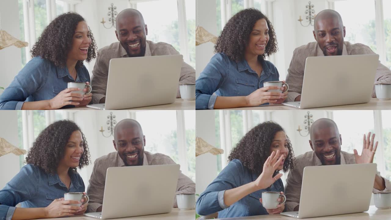 夫妇坐在家里的桌子旁，用笔记本电脑进行视频通话