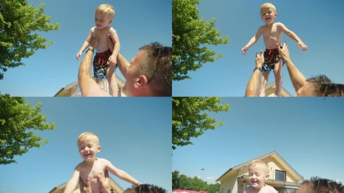低角度视角的父亲在游泳池玩耍时将他的宝贝儿子抛向空中
