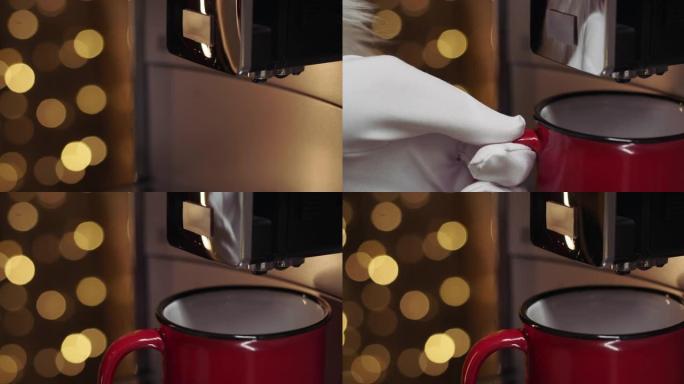 圣诞老人的手的特写镜头将杯子放入咖啡机中，背景为圣诞灯