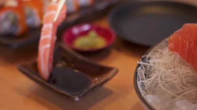 SLO MO筷子将芥末放在鲑鱼生鱼片上，然后浸入shoyu。
