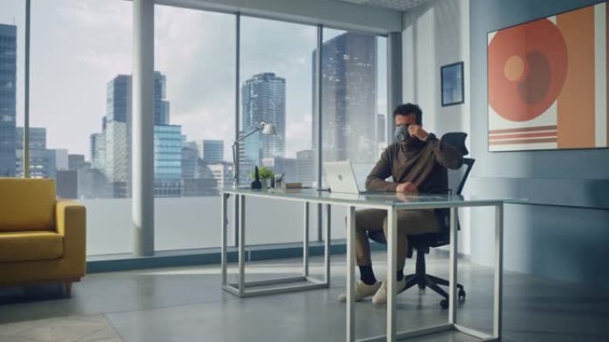 富有魅力的阿拉伯商人的肖像坐在他的办公桌前，在大城市办公室的笔记本电脑上工作。成功的数字企业家为电子