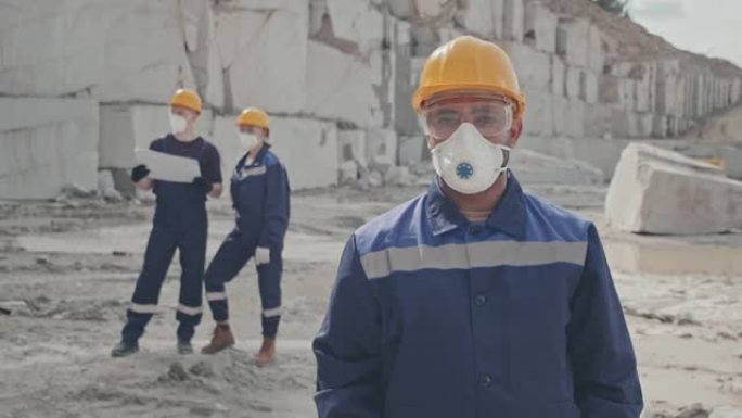 戴着防尘面具的工人在花岗岩采石场摆姿势