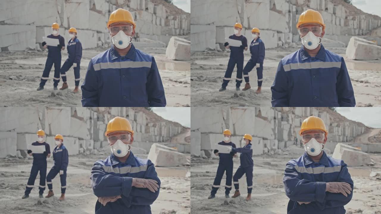 戴着防尘面具的工人在花岗岩采石场摆姿势