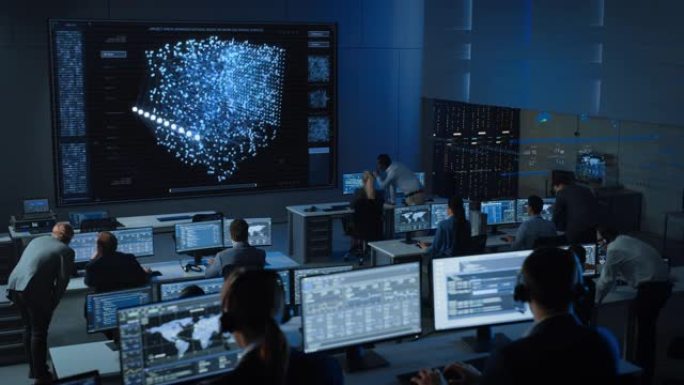 在现代监控办公室工作的工程师的静态镜头，在大屏幕上显示实时神经网络。监控室大数据科学家和管理人员坐在