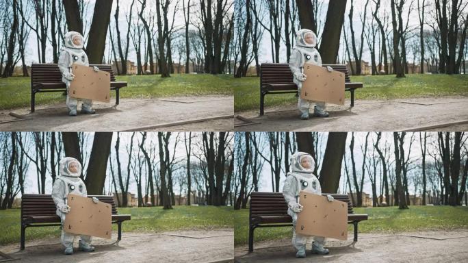 身穿宇航服的悲伤男子坐在公园的长椅上，举着车载模型标志。可怜的宇航员看着远处。穿着白色未来派西装的情