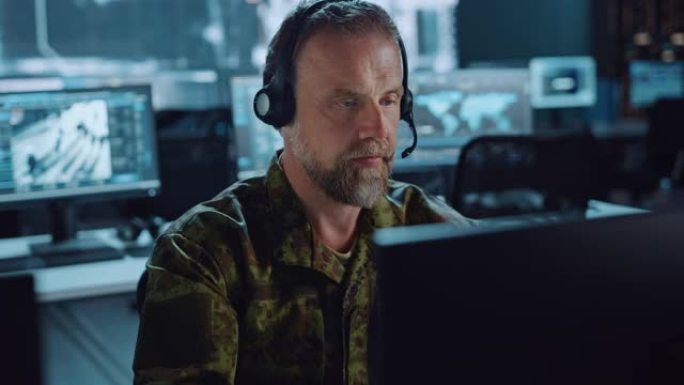 头戴式耳机中的胡须军事监视官在中央办公室中心工作，用于网络操作，控制和监视，以管理国家安全，技术和军