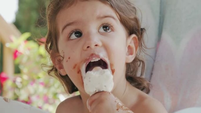 可爱的蹒跚学步的女孩吃冰淇淋，弄得一团糟。