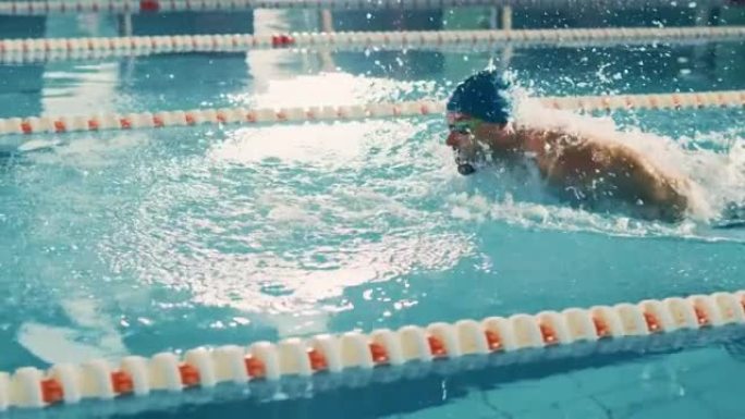 男子游泳比赛成功，在奥林匹克游泳池游泳。职业运动员决心用蝶式赢得冠军。彩色电影镜头。侧视图跟踪慢动作