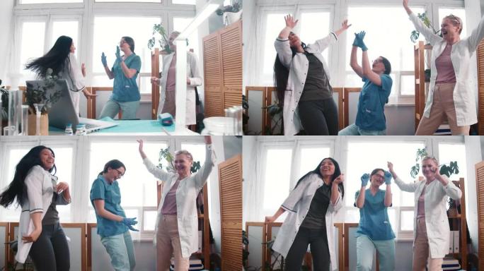 战胜冠状病毒大流行。三个有趣的不同年龄快乐的女医生在诊所实验室跳舞庆祝成功。