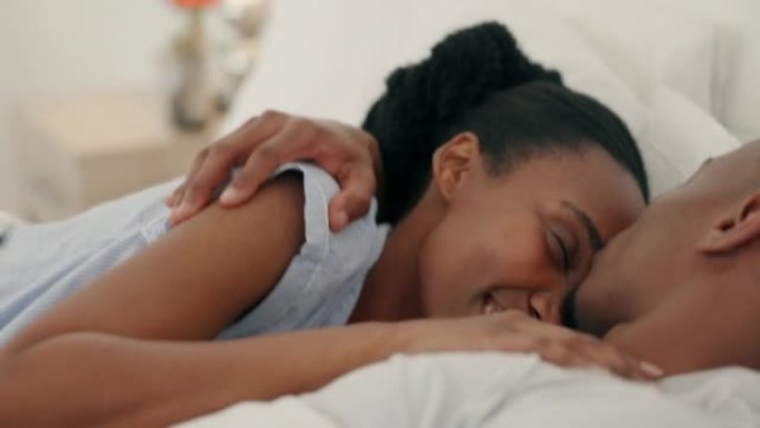 爱、拥抱和亲吻卧室的黑人夫妇在家放松浪漫、团结和亲密。快乐，情人节和微笑的非洲年轻人在特殊的蜜月中调