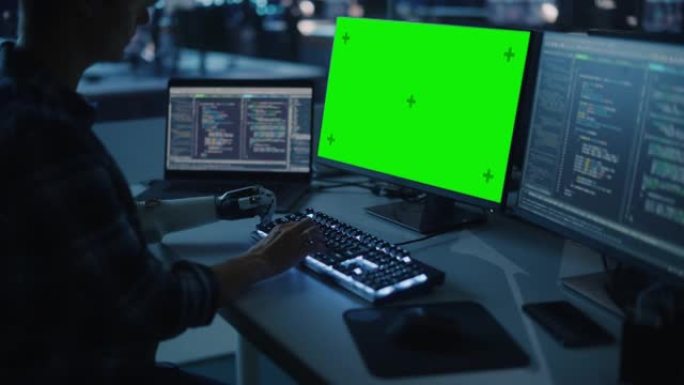 夜间办公室: 残疾人使用假肢在绿屏色度键计算机上工作。快速自然地使用肌电仿生手在夜间为软件键入代码。