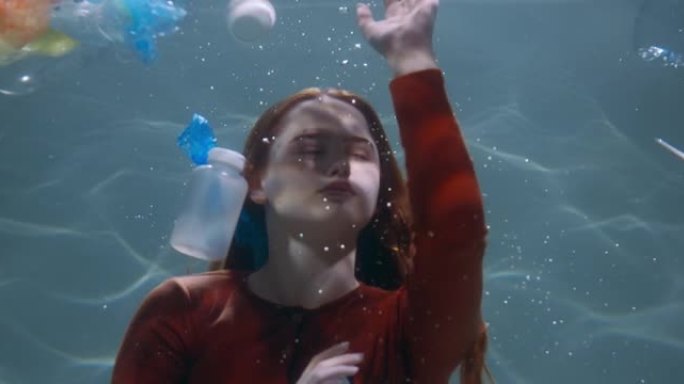 不小心处理塑料垃圾。水下慢动作下一次性废流中年轻女子的电影镜头。