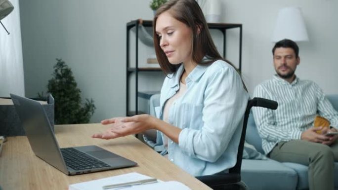 开朗的残疾妇女在家中使用笔记本电脑进行在线视频通话和挥手