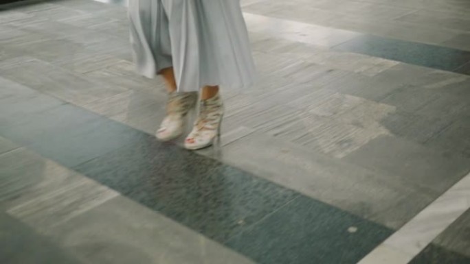 穿着高跟鞋走在购物中心的女人