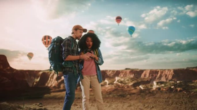 年轻的徒步旅行者夫妇正在落基峡谷谷顶部的智能手机上查看旅游信息和方向。冒险的背包客。国家公园热气球节