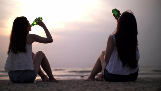 日落时间两名妇女在海滩上喝酒放松
