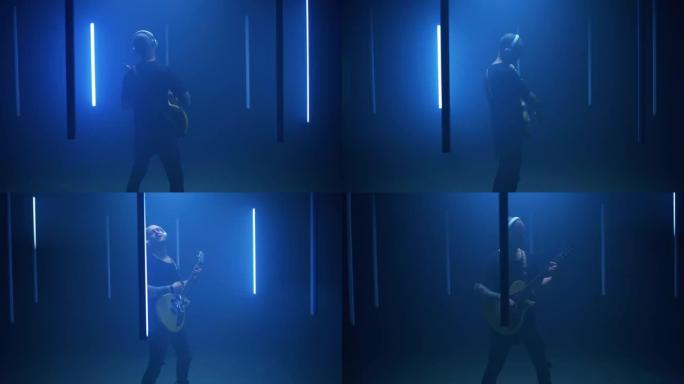 男吉他手在蓝色的灯中演奏歌曲