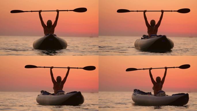 兴奋的年轻女子在克罗地亚亚得里亚海的日落海洋上举着桨