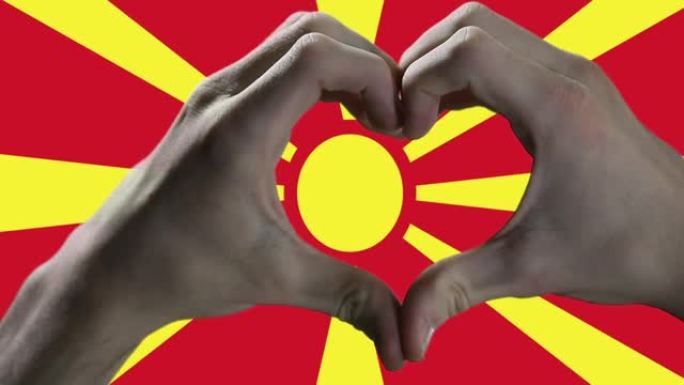 双手在北马其顿国旗上显示心脏标志。