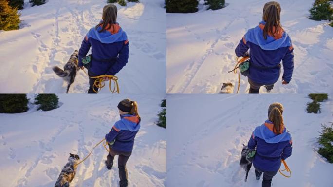 SLO MO女人和一只狗在斜坡上的雪地里涉水