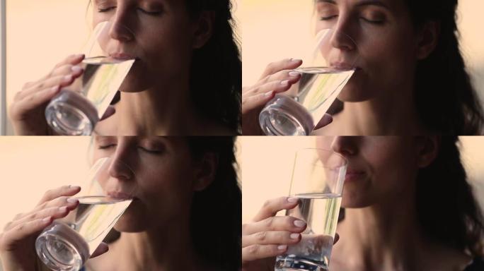 特写镜头年轻女子喝一杯静止的天然水