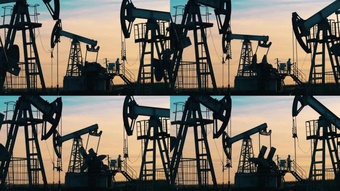 石油工人站在油泵千斤顶之间。石油行业，原油价格概念。