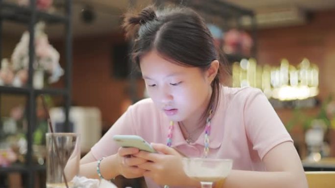 亚洲美丽的少女在餐厅使用智能手机