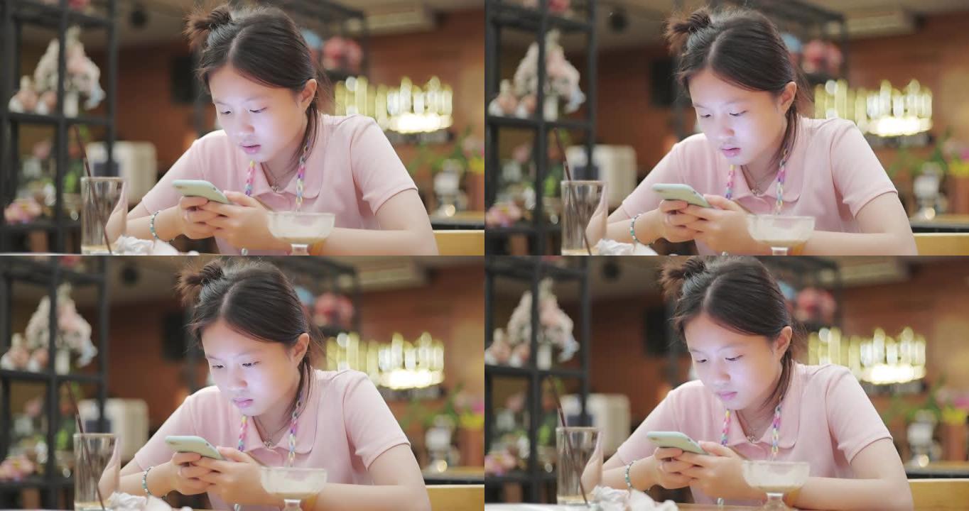亚洲美丽的少女在餐厅使用智能手机