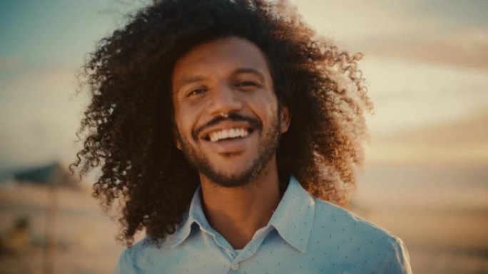 一个快乐的年轻成年男性的肖像，非洲裔头发和鼻环刺穿，为相机摆姿势。英俊多样的多种族黑人男性微笑。暖色